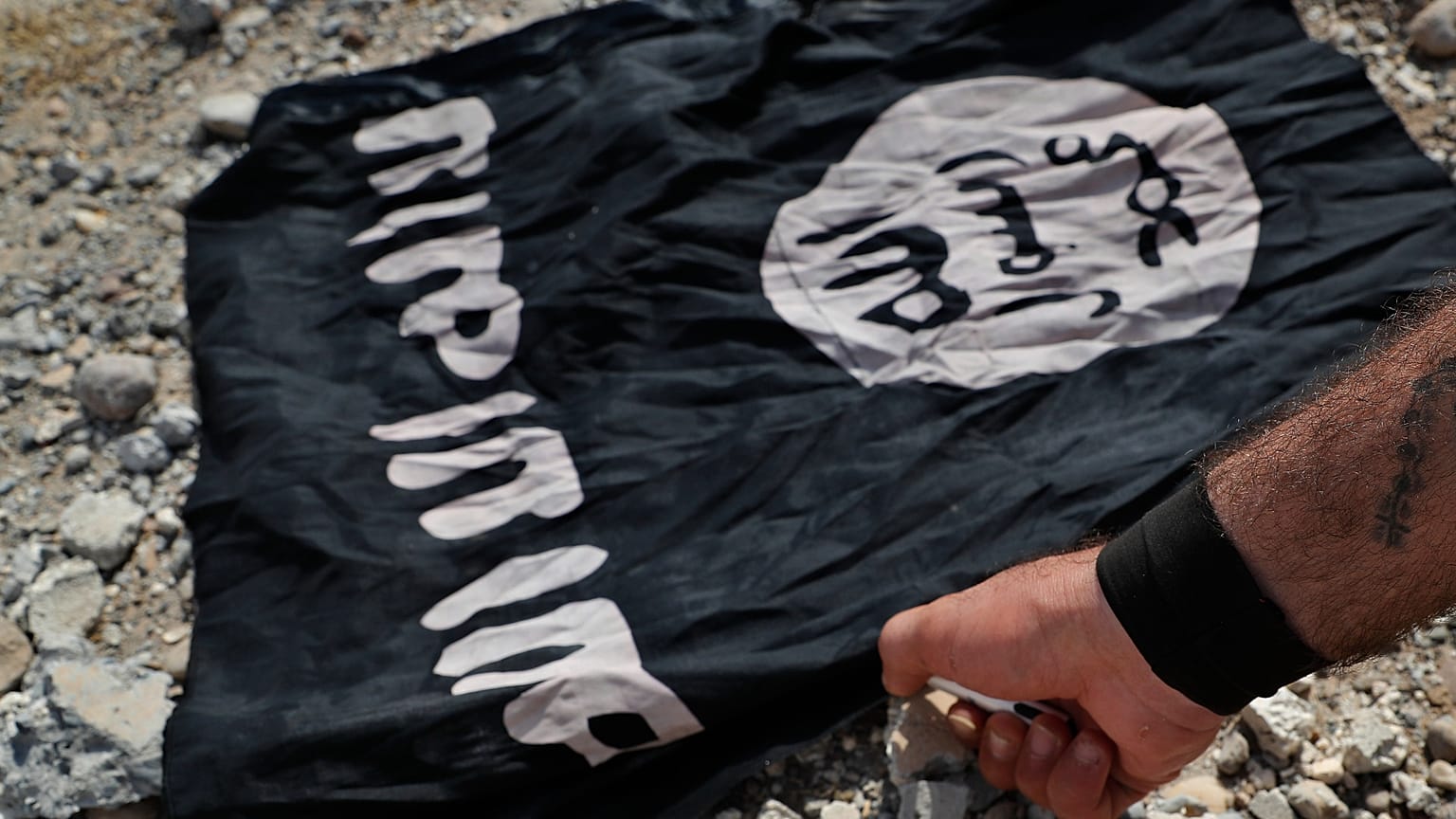 Bojownik chrześcijańskiej milicji syryjskiej pali flagę IS na linii frontu po zachodniej stronie Raqqa, 17 lipca 2017 r.