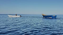 Un bateau utilisé par les migrants pour traverser la Méditerranée, remorqué de la plage de Tripiti au Karave du port de Gavdos, en Grèce, le lundi 7 juillet 2025.