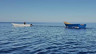 Un bateau utilisé par les migrants pour traverser la Méditerranée, remorqué de la plage de Tripiti au Karave du port de Gavdos, en Grèce, le lundi 7 juillet 2025.