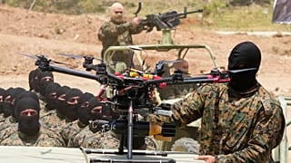 Bir Hizbullah savaşçısı Lübnan'ın güneyindeki Aaramta'da bir eğitim tatbikatı sırasında silahlı bir insansız hava aracının yanında dururken, 21 Mayıs 2023