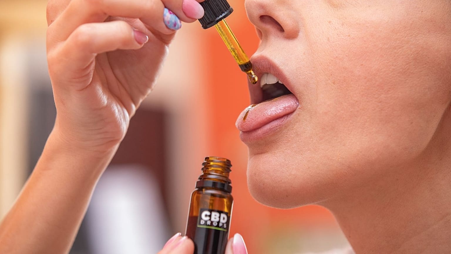A woman uses CBD drops.