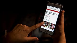 Una mujer lee un artículo en su teléfono móvil sobre las posibilidades de las noticias falsas.
