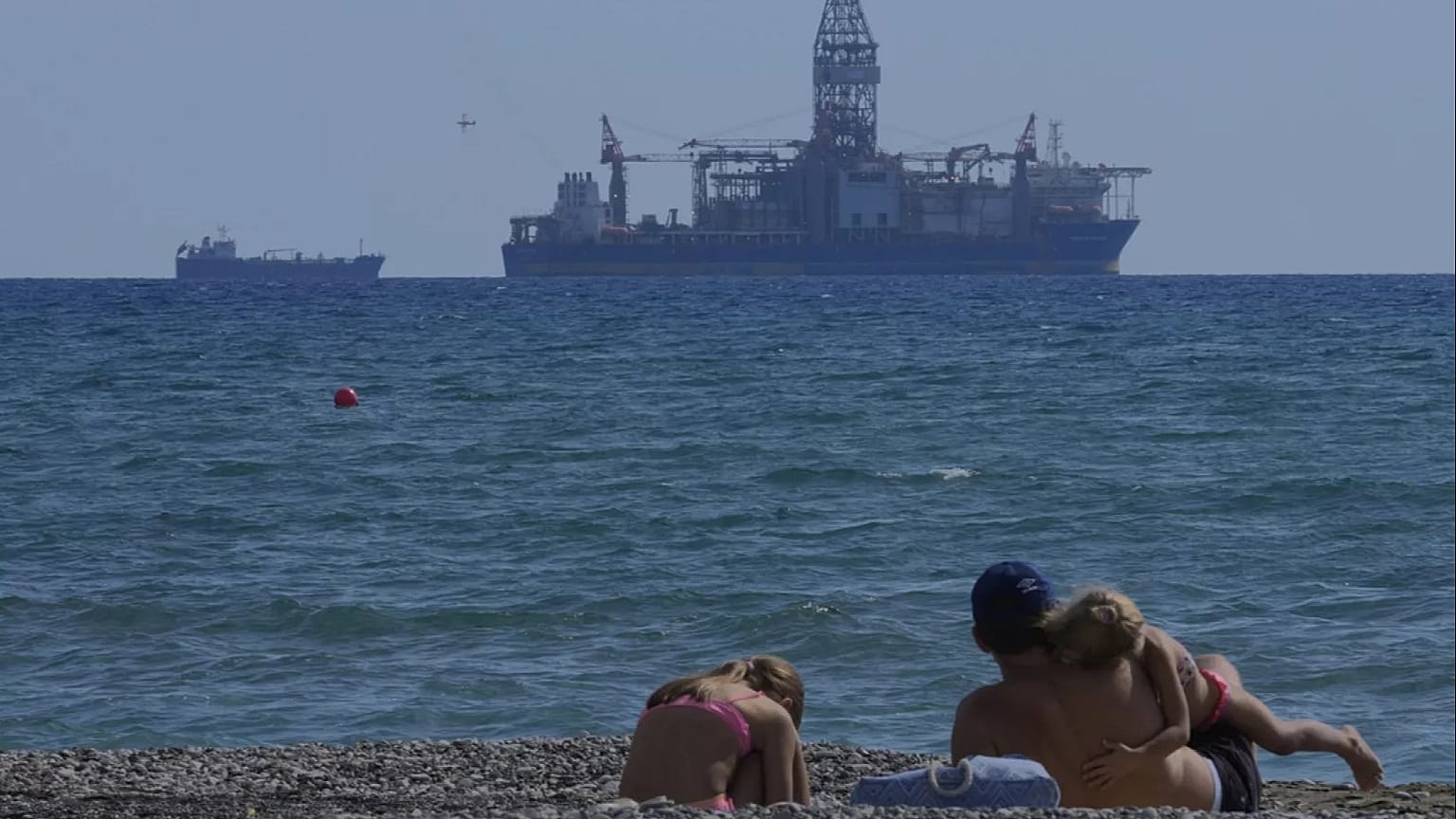 Une famille assise au bord de la mer avec vue sur le navire de forage "Tungsten Explored", dans la ville côtière méridionale de Larnaca, à Chypre, le 3 novembre 2021. 