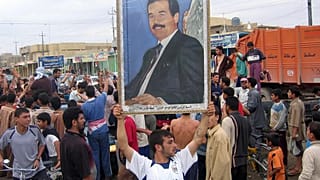 رجل يرفع صورة  للرئيس العراقي المخلوع صدام حسين احتجاجًا على حكم إعدامه في الفلوجة، العراق، يوم الاثنين 6 نوفمبر/تشرين الثاني 2006.  