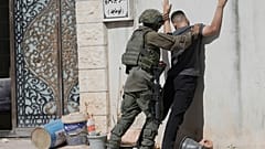 جندي إسرائيلي يفتش رجل فلسطيني في مخيم طولكرم للاجئين بالضفة الغربية، الأحد 6 يوليو 2025.  