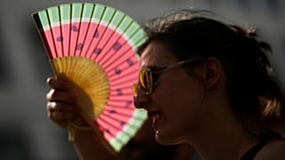 Ein Fächer als Sonnenschutz, um die hohen Temperaturen in Lissabon zu ertragen, 28. Juni 2025