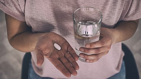 A woman prepares to take a pill.