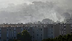 Rauch steigt hinter Gebäuden während eines Waldbrandes am Dienstag, 8. Juli 2025, im Stadtteil La Castellane in Marseille, Südfrankreich, auf.