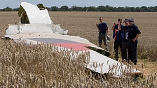 ARQUIVO - Investigadores australianos e holandeses examinam um pedaço do avião do voo 17 da Malaysia Airlines, perto da aldeia de Hrabove, a 1 de agosto de 2014
