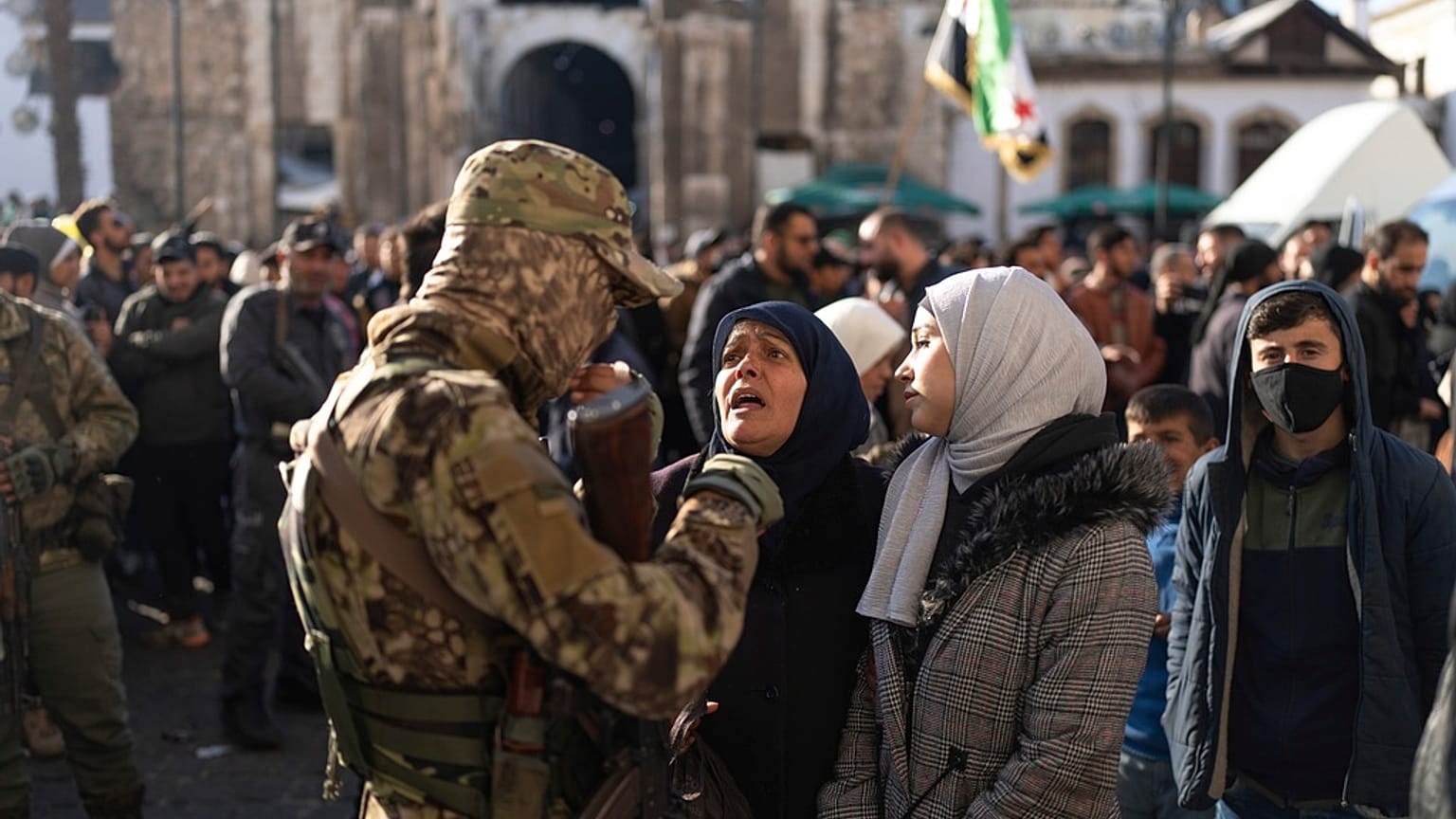 مرأتان تتحدثان مع ضابط أمن خارج الجامع الأموي في انتظار آخر المستجدات بعد حادثة التدافع التي وقعت أثناء صلاة الجمعة في دمشق