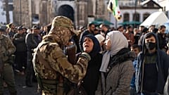 مرأتان تتحدثان مع ضابط أمن خارج الجامع الأموي في انتظار آخر المستجدات بعد حادثة التدافع التي وقعت أثناء صلاة الجمعة في دمشق