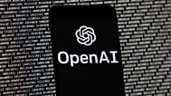  يظهر شعار OpenAI على هاتف محمول أمام شاشة حاسوب تحتوي على بيانات ثنائية عشوائية، 9 مارس/آذار 2023، في بوسطن. 