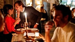 Ein Paar unterhält sich bei einem Drink und einem Abendessen bei Kerzenlicht in der Brasserie Surrealiste in Brüssel.