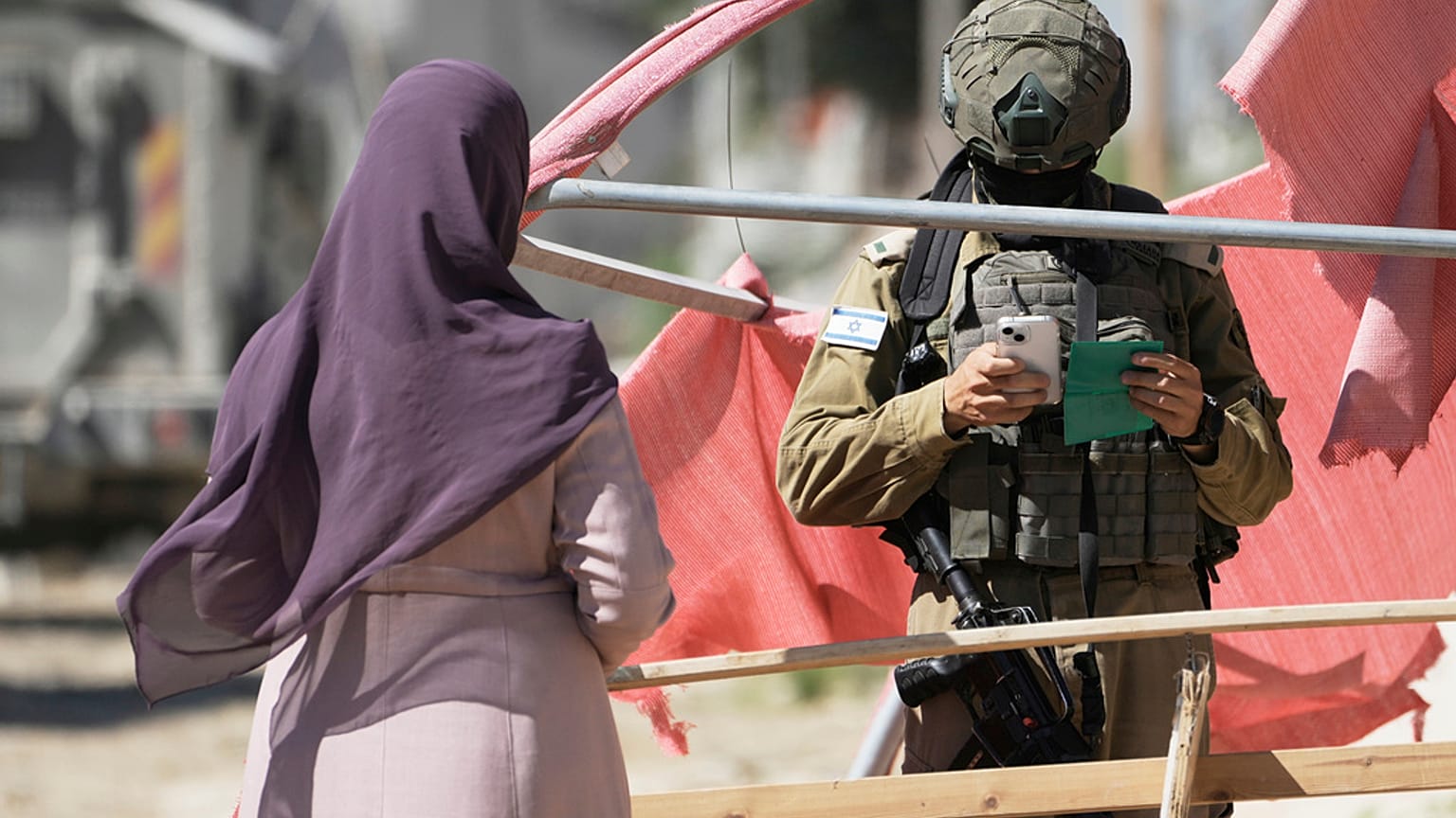 جندي إسرائيلي يدقق في وثائق امرأة فلسطينية في مخيم طولكرم للاجئين الفلسطينيين في الضفة الغربية 2025