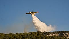Ein Löschflugzeug lässt Wasser ab, während ein Waldbrand in Rafina, östlich von Athen, Griechenland, am Donnerstag, den 3. Juli 2025, wütet. Mehrere Häuser in der Gegend wurden durch das Feuer zerstört.