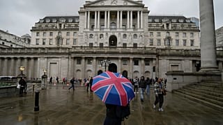 A woman with an umbrella stands in front of the Bank of England, at the financial district in London. 3 November 2022.