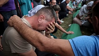 Men mourn beside the coffins of their relatives, victims of the 1995 Srebrenica genocide, ahead of the mass burial in Potocari, Bosnia, Thursday, July 10, 2025. 