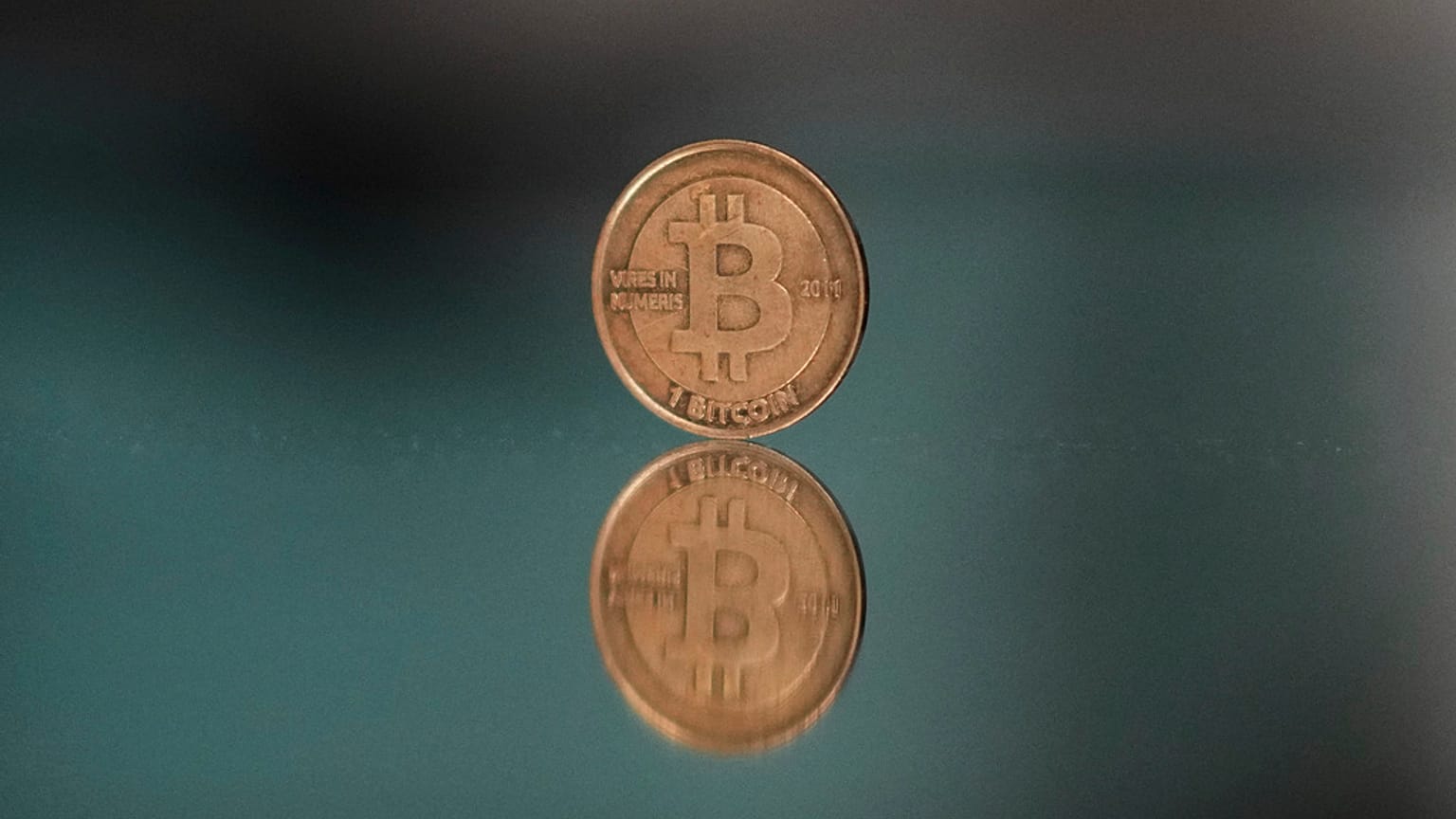 Egy bitcoin tokent helyeznek egy tükörre egy fényképhez a csehországi Prágában, 2025. május 11-én.