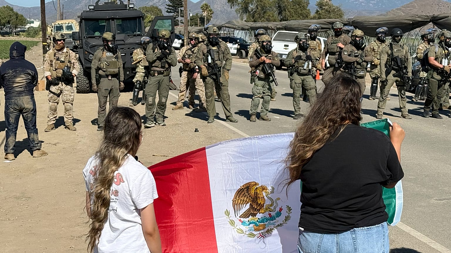 Manifestantes sostienen una bandera frente a agentes federales que bloquean una carretera durante una redada de inmigración en Camarillo, California, el 11 de julio de 2025.