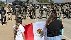 Manifestantes sostienen una bandera frente a agentes federales que bloquean una carretera durante una redada de inmigración en Camarillo, California, el 11 de julio de 2025.