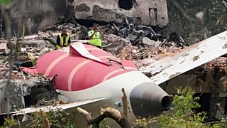 Официальные лица осматривают место крушения самолета авиакомпании Air India на крыше здания в Ахмадабаде, Индия, пятница, 13 июня 2025 года.