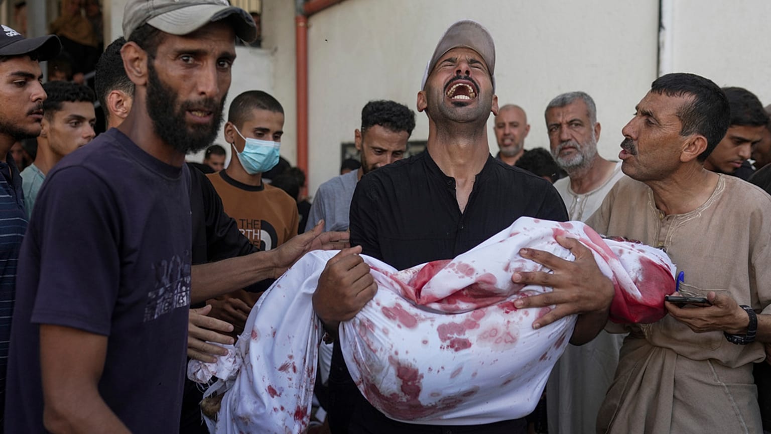 رجل فلسطيني يحمل جثة طفله ، الذي قتل في غارة جوية عسكرية إسرائيلية على غزة ، في مستشفى الشفاء في مدينة غزة ، السبت 12 يوليو / تموز 2025. 