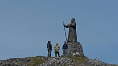 Turisták állnak Hans Egede szobra előtt a grönlandi Nuukban 2025. június 22-én, vasárnap.