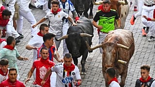 Des fêtards courent aux côtés des taureaux de combat de Miura lors de la dernière course de taureaux au festival de San Fermín à Pampelune, en Espagne, lundi 14 juillet 2025