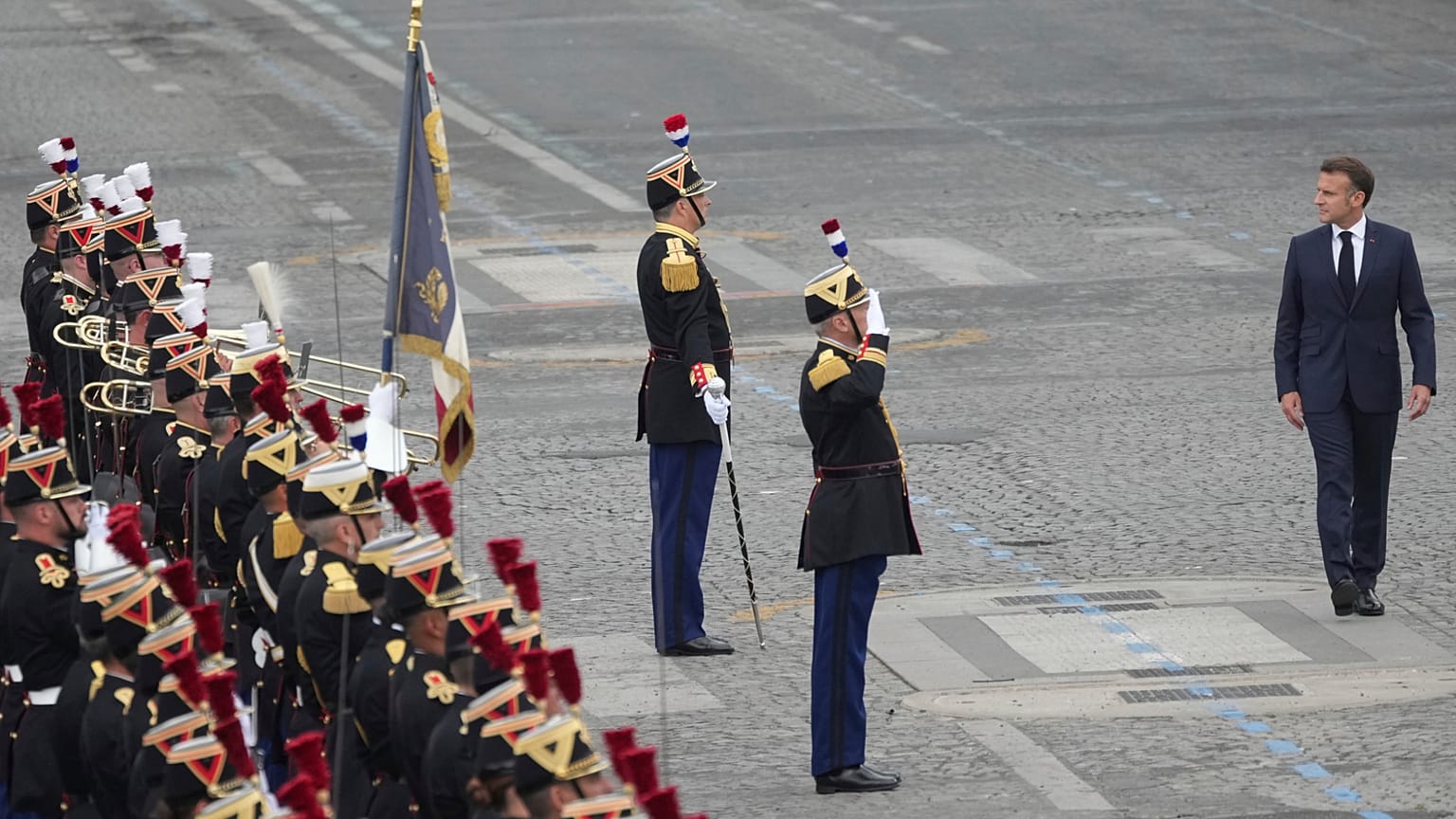 O Presidente francês, Emmanuel Macron, à direita, revê a Guarda Republicana durante o desfile do Dia da Bastilha, segunda-feira, 14 de julho de 2025, em Paris