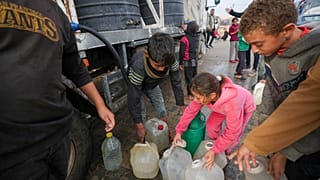 أطفال يجمعون المياه من شاحنة في مخيم خيام للنازحين الفلسطينيين في دير البلح، وسط قطاع غزة، الخميس 16 كانون الثاني/يناير 2025. 