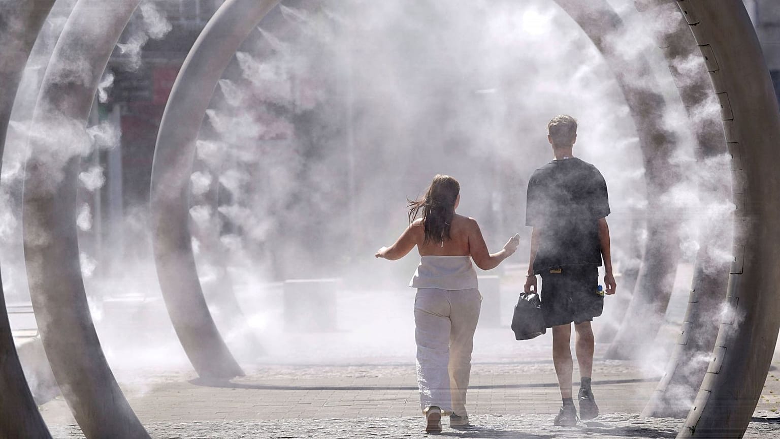A couple walk through a cooling water feature as the third heatwave of the summer hits the UK, in Dover, 11 July 2025. 