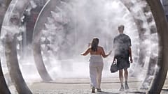 A couple walk through a cooling water feature as the third heatwave of the summer hits the UK, in Dover, 11 July 2025. 