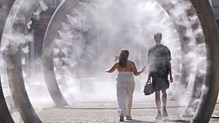 A couple walk through a cooling water feature as the third heatwave of the summer hits the UK, in Dover, 11 July 2025.