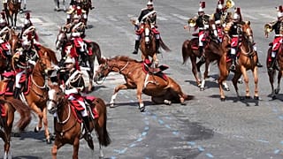 Ein Pferd rutscht auf dem Bürgersteig während der Parade zum Bastille-Tag am Montag, den 14. Juli 2025, in Paris.