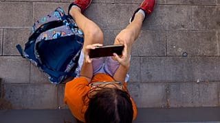 Un niño juega con el teléfono de su padre a la salida del colegio en Barcelona, España.