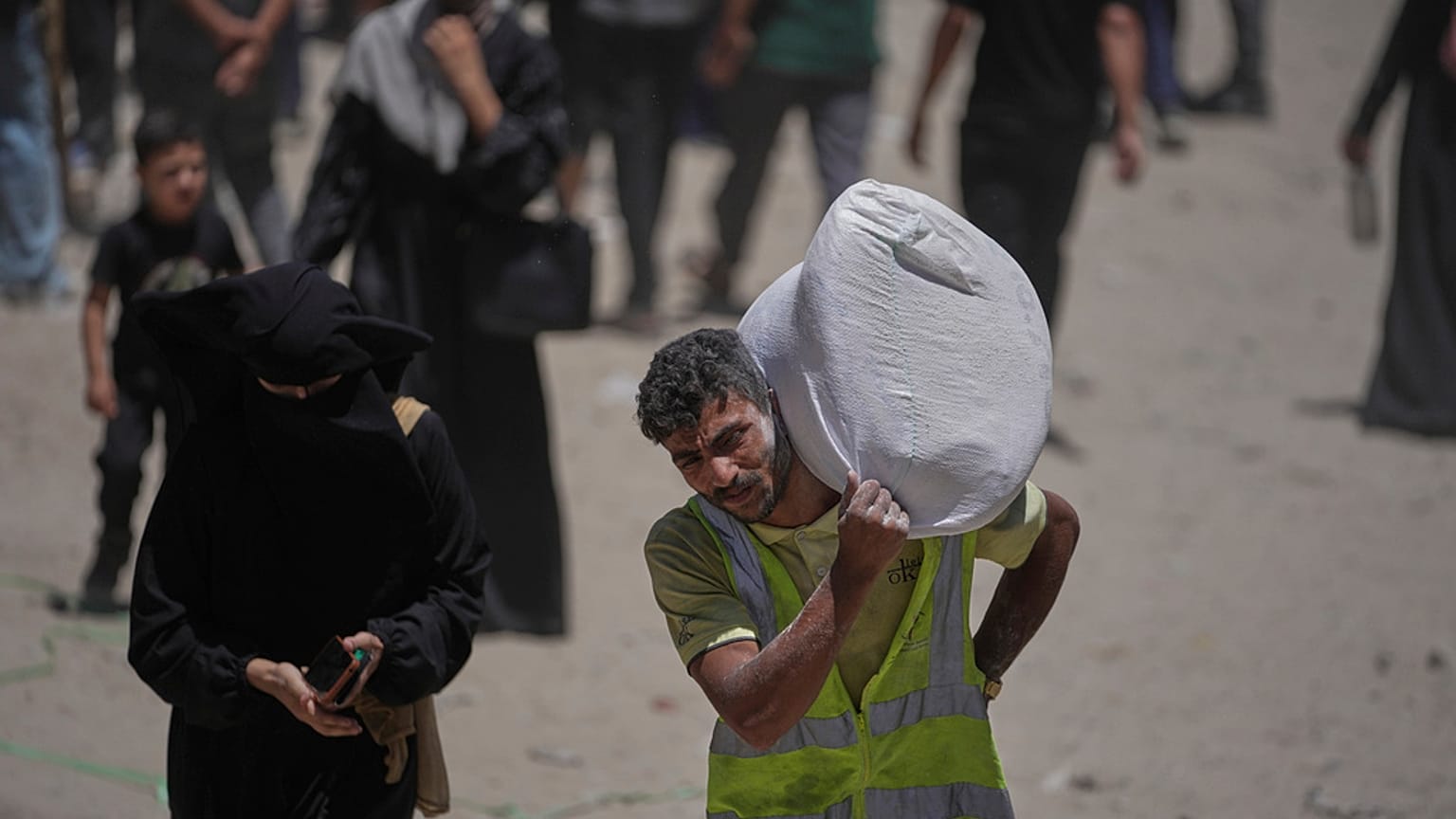  فلسطينيون يحملون أكياس الدقيق التي وزعها برنامج الغذاء العالمي في مدينة غزة، شمال قطاع غزة، السبت 12 يوليو/تموز 2025.