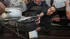 فلسطينيون يتدافعون للحصول على الطعام المقدم كتبرعات في مطبخ مجتمعي بمدينة غزة، شمال قطاع غزة، الإثنين 14 يوليو 2025. 