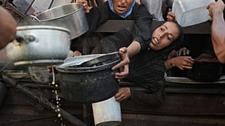 فلسطينيون يتدافعون للحصول على الطعام المقدم كتبرعات في مطبخ مجتمعي بمدينة غزة، شمال قطاع غزة، الإثنين 14 يوليو 2025. 