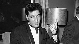 El cantante Elvis Presley luce sus anillos y puños de encaje en el interior de su vagón privado en la Union Station de Los Ángeles el 20 de abril de 1960, a su llegada para rodar una película.