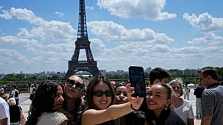 يلتقط السياح صورة سيلفي مع برج إيفل في الخلفية