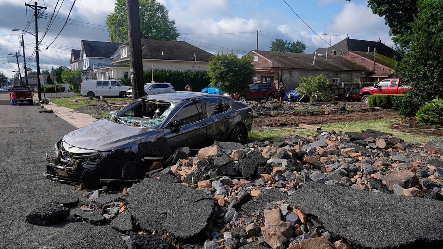 Debris, rubble and a damaged car lie on a street after flooding from rains in the area of North Plainfield, N.J., Tuesday, July 15, 2025.