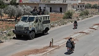 Suriye hükümetine bağlı güvenlik güçleri Dera'nın Busra el-Harir köyünde zırhlı araçlarının üzerinde oturuyor, 14 Temmuz 2025.