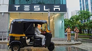 Policemen stand guard as a three-wheeler auto-rickshaw drives past India's first Tesla showroom to be inaugurated in Mumbai, India, Tuesday, July 15, 2025.