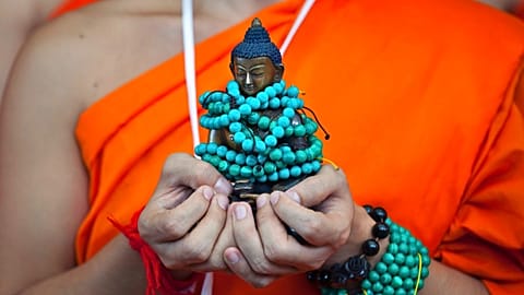 FILE: A Thai Buddhist monk carries a statue of Buddha in Dharmsala, India, Friday, Sept. 7, 2018