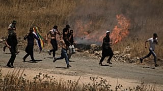 دروز سوريون يفرون من الغاز المسيل للدموع الذي أطلقه جنود إسرائيليون أثناء احتجاجهم على الجانب السوري من الحدود مع إسرائيل الأربعاء 16 يوليو/تموز 2025.