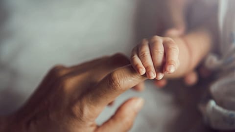 Newborn baby holding mother's hand