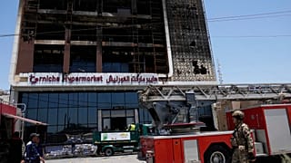 Los bomberos se reúnen frente a un edificio de hipermercado en llamas en Kut, Irak