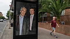 Commuters walk past a bus stop as activists put up a poster showing US President Donald Trump and Jeffrey Epstein near the US Embassy in London, 17 July 2025