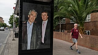 Commuters walk past a bus stop as activists put up a poster showing US President Donald Trump and Jeffrey Epstein near the US Embassy in London, 17 July 2025