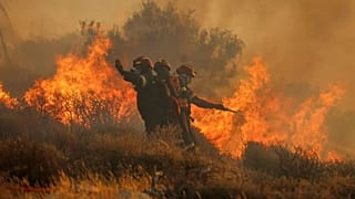 Los bomberos utilizan una manguera mientras intentan extinguir las llamas cerca de la ciudad de Lerapetra, en la costa sur de la isla de Creta, Grecia, el 3 de julio.